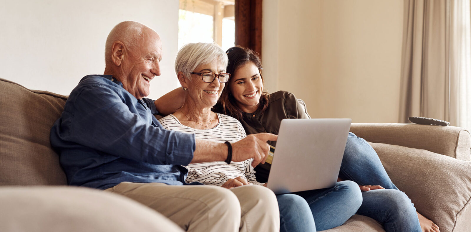 Shot of a young woman using a laptop and credit card with her elderly parents on the sofa at home